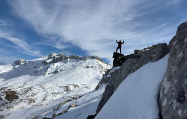 The position of the successful, brave and leading mountaineer on the cliffs with a magnificent winter view - 763991323