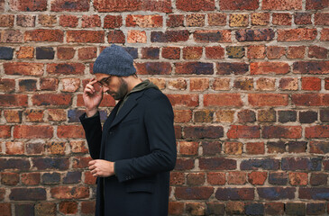 Fashion, man and thinking on brick wall with glasses for trendy, cool and style for urban with...