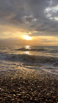 Sunrise sea, view from shoreline. Beach with pebbles. Sea beach shore with waves. Pebble stone beach on sunset. Shore landscape on Spain resort. Ocean shoreline scenic. Waves in sea. Ocean sunset