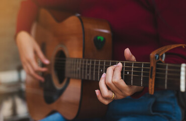 Close-up of female hands holding guitar chords and playing acoustic guitar