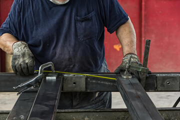Locksmith processes steel sheets and measures a distance.