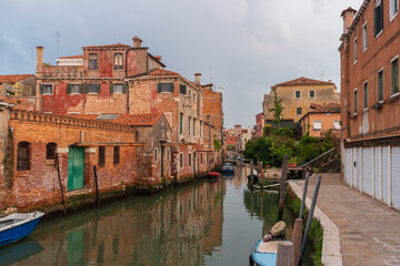 Venice, Italy. Old Venetian district with residential buildings and a water canal with moored boats.