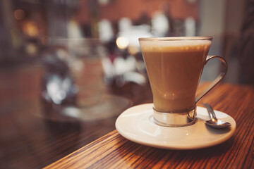 Coffee cup in coffee shop. Coffee latte on the wood desk in coffee shop cafe restuarant, Italy. Brake time with a mug of coffee and city view though window. 