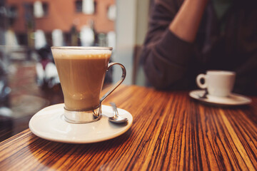 Coffee cup in coffee shop. Coffee latte on the wood desk in coffee shop cafe restuarant, Italy. Brake time with a mug of coffee and city view though window. 