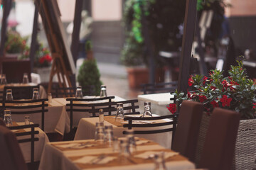 Beautiful tables in a street cafe in rainy day, Milano, Italy. Street view of a coffee terrace with tables and chairs in europe. 