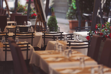 Beautiful tables in a street cafe in rainy day, Milano, Italy. Street view of a coffee terrace with tables and chairs in europe. 