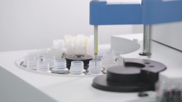 Close up in a research laboratory, a scientist places glass vials in machine equipment for chemical or medical analysis test. High quality 4k footage