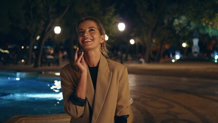 Carefree girl communicating smartphone at dark city square. Happy woman talking