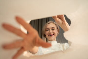 A joyful woman is captured looking inside a cardboard box, as she appears to be in the process of...