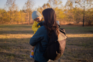 A woman with a backpack travels with her son, enjoying a family hike in the forest. They embrace an active lifestyle, sporting hiking gear and exploring eco-friendly tourism.