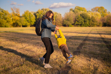 A woman with a backpack travels with her son, enjoying a family hike in the forest. They embrace an...