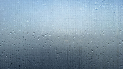 Foggy opaque glass with many small and large drops of water. The upper part is lighter than the...