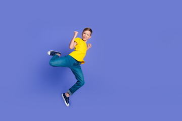 Full length photo of cheerful funny pupil boy wear stylish yellow clothes fly air fist yes success isolated on violet color background