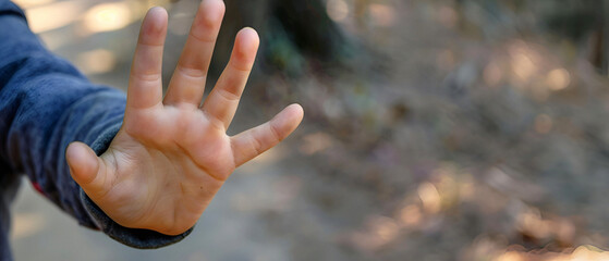 A close-up of a child's hand showing a stopping gesture - obrazy, fototapety, plakaty