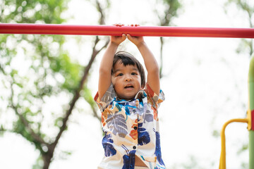 Adorable preschool boy enjoying bar lifting in outdoor playground in city park