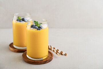 Refreshing and healthy mango smoothie with coconut flakes and fresh blueberries - 764037319