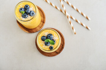 Refreshing and healthy mango smoothie with coconut flakes and fresh blueberries - 764037349