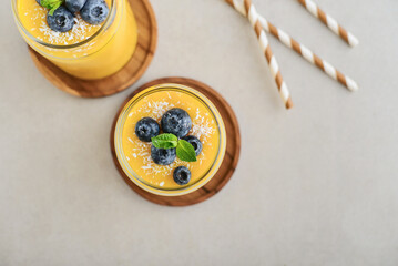 Refreshing and healthy mango smoothie with coconut flakes and fresh blueberries - 764037387