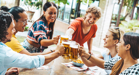Happy friends celebrating drinking beer pint at park outdoor - Young people talking and laughing together at brewery pub garden - Friendship, youth and beverage concept - obrazy, fototapety, plakaty