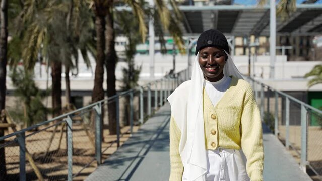 Muslim trendy girl walking in the city. Black girl happy smiling to the camera in a park. 