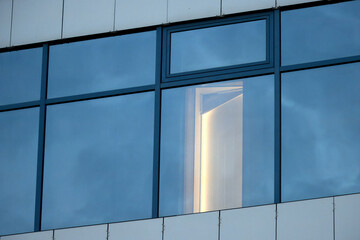 An open door seen from outside of the building in a modern office building on Friday afternoon, lights on after working hours, energy saving, weekend office work, being fired from a job.
