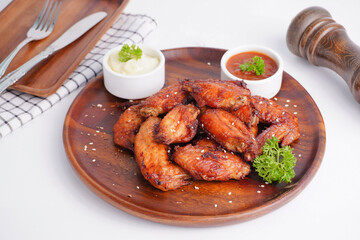 Cooked grilled chicken wings marinated with seasonings Placed on an old wooden tray on a white background