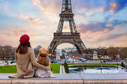 Family city travel concept with a mother and her daughter looking at the beautiful sunset view of the Eiffel Tower in Paris, France