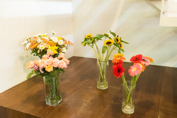 Sunflowers and rose in glass vase on wooden table..