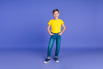 Fototapeta na wymiar Full length photo of nice cheerful boy arms in pockets dressed yellow stylish clothes empty space isolated on violet color background