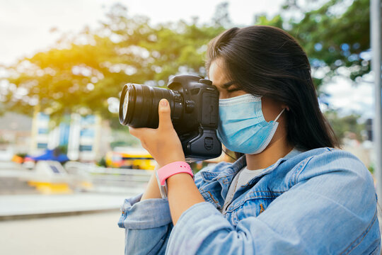 Young beautiful woman in the park with face mask taking photos