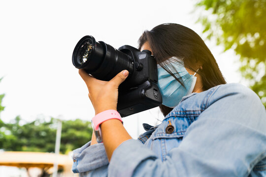 Young beautiful woman in the park with face mask taking photos