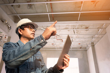 home inspector with a digital tablet. examines the building structure and ceiling home construction...