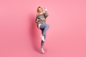 Full length photo of optimistic lovely woman dressed print sweater jumping win lottery shout yeah isolated on pink color background