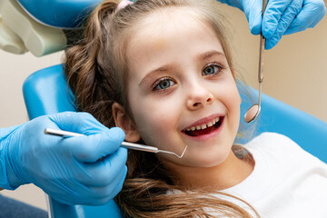 dentist, doctor examines the oral cavity of a little girl, uses a mouth mirror, baby teeth...