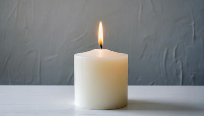 Obraz na płótnie Canvas White burning candle white table. Gray backdrop.