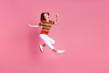 Fototapeta na wymiar Full body portrait of energetic cheerful girl jump raise fists empty space ad isolated on pink color background