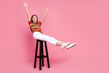 Full length portrait of overjoyed pretty girl sit stool raise arms empty space isolated on pink color background - obrazy, fototapety, plakaty