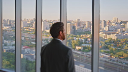 Stylish executive looking window rear view. Pensive businessman admiring city