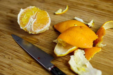 Orange peeled and cut on wooden cutting board with peel and japanese knife