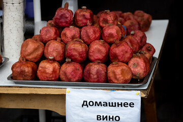 Tray of pomegranates displayed with a sign that reads in Georgian, "pomegranate drink."