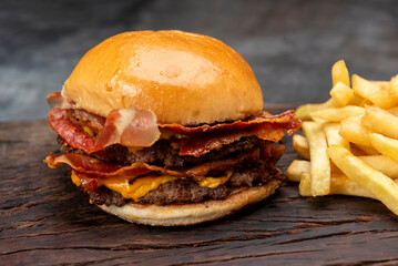 variety of homemade beef burgers with onion cucumber dressings tomato chedar cheese lettuce mayonnaise mustard ketchup barbecue with potato bun and french fries on wooden board