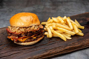 variety of homemade beef burgers with onion cucumber dressings tomato chedar cheese lettuce mayonnaise mustard ketchup barbecue with potato bun and french fries on wooden board