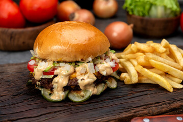 variety of homemade beef burgers with onion cucumber dressings tomato chedar cheese lettuce mayonnaise mustard ketchup barbecue with potato bun and french fries on wooden board