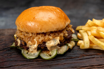 variety of homemade beef burgers with onion cucumber dressings tomato chedar cheese lettuce mayonnaise mustard ketchup barbecue with potato bun and french fries on wooden board