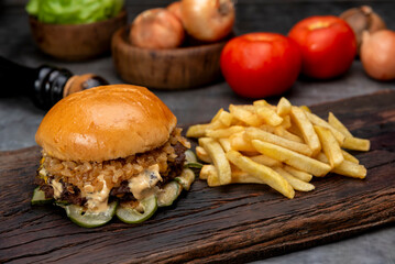 variety of homemade beef burgers with onion cucumber dressings tomato chedar cheese lettuce mayonnaise mustard ketchup barbecue with potato bun and french fries on wooden board