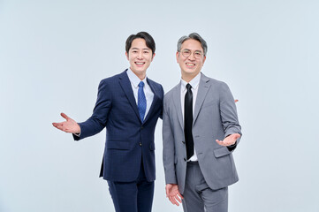 A young office worker man wearing a suit and glasses and a middle-aged man are posing with a variety of confident expressions together.