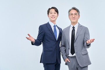 A young office worker man wearing a suit and glasses and a middle-aged man are posing with a variety of confident expressions together.