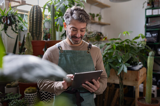 Plant shop owner using a digital tablet in store for electronic banking - Powered by Adobe