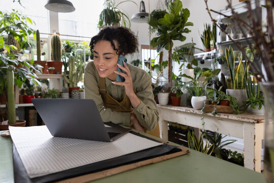 Small business owner helping a customer on the phone in her plant store
