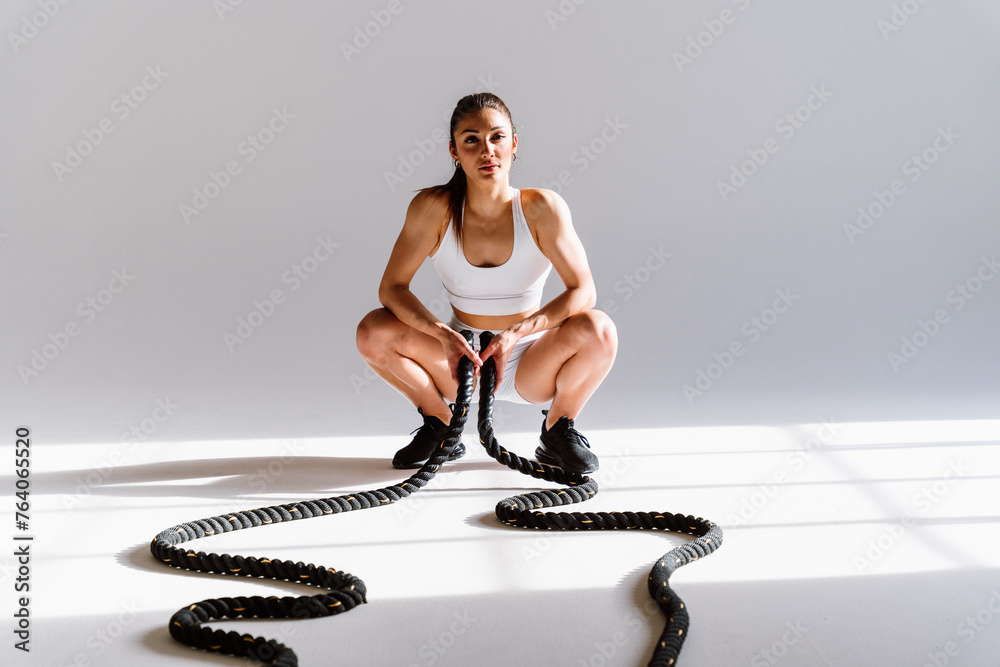 Poster Young female athlete training in a gym using sport equipment